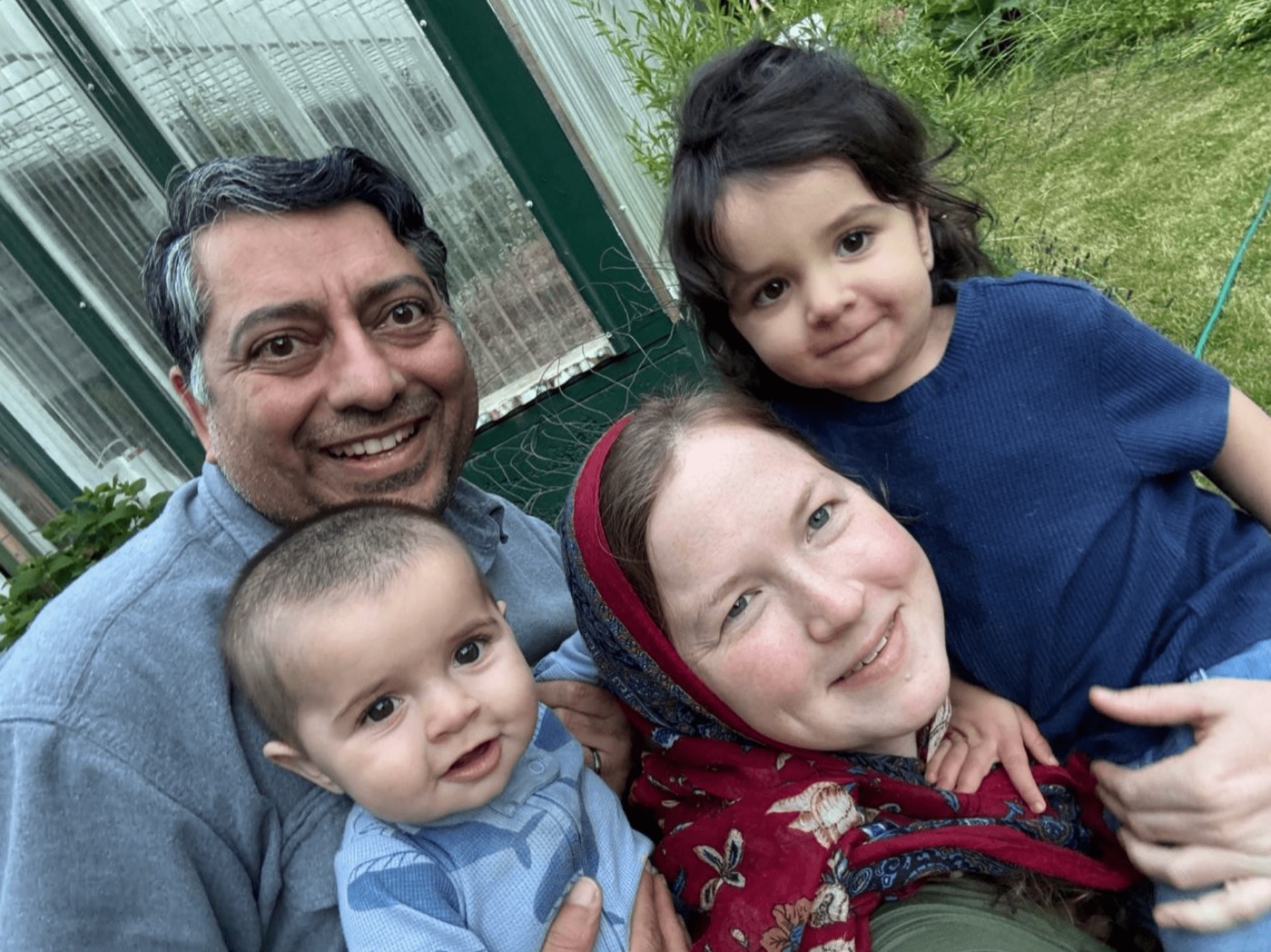 Zahid and Melissa Chaudhry with their two children by the greenhouse, summer 2025.